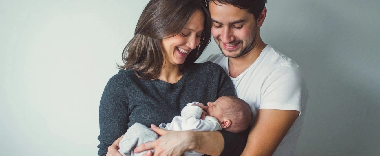 Intended parents holding their newborn baby