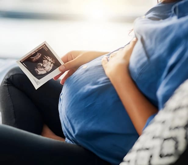 Proud surrogate standing beside a baby cradle after being matched with intended parents
