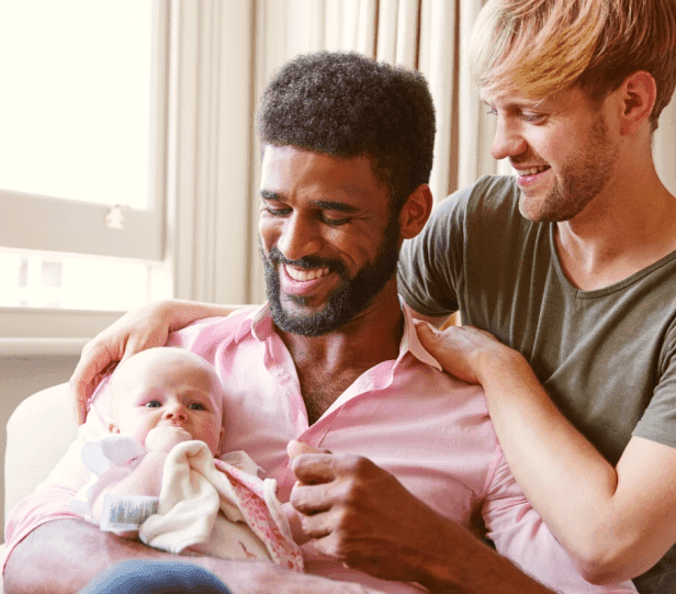 Same-sex couple holding their newborn baby after a successful surrogacy journey