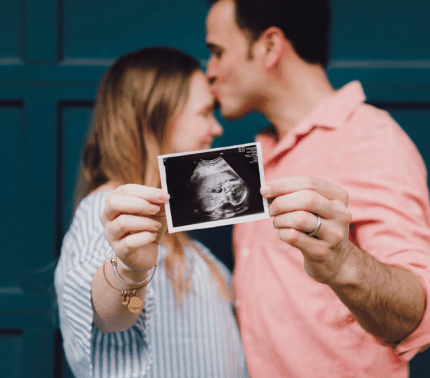Intended parents viewing ultrasound photo during surrogate pregnancy in Canada